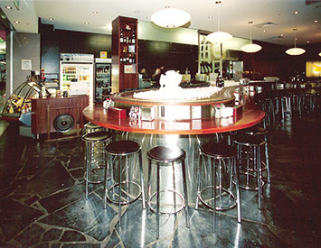 Curved solid timber high tables in Jarrah with stainless steel surround.