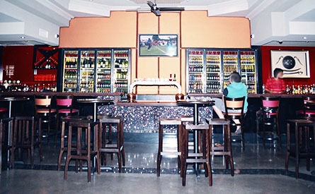 Routed painted panels with granite tops on bar and DJ booth and open shelving for bottle storage.