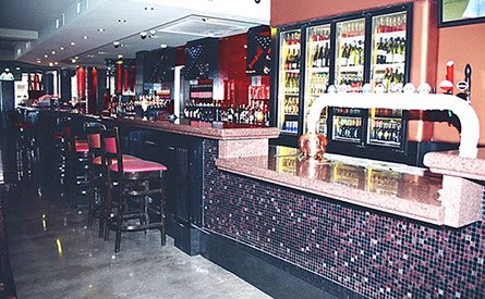 Routed painted panels with granite tops on bar and DJ booth and open shelving for bottle storage.